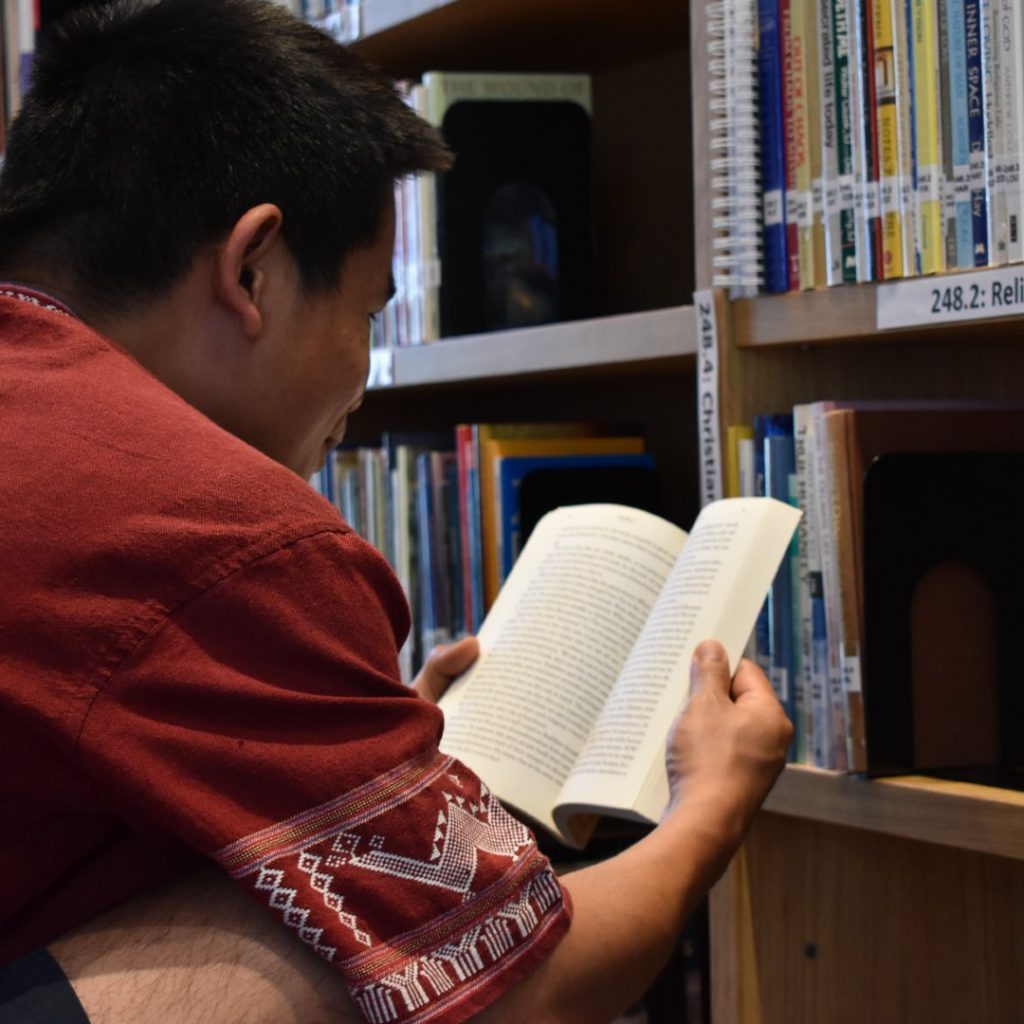 man reading book in library
