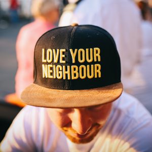 man with love your neighbour on his hat