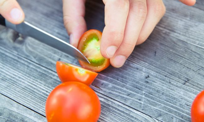 hands with knife chopping tomato