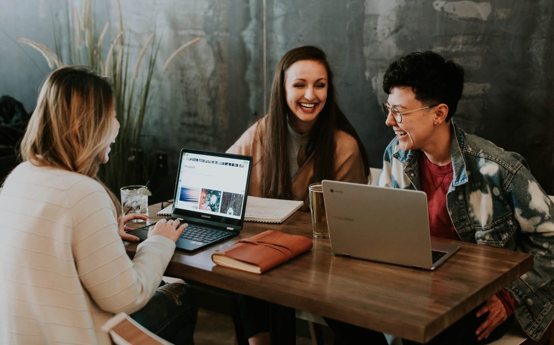 3 women sitting around a table with tablets learning English