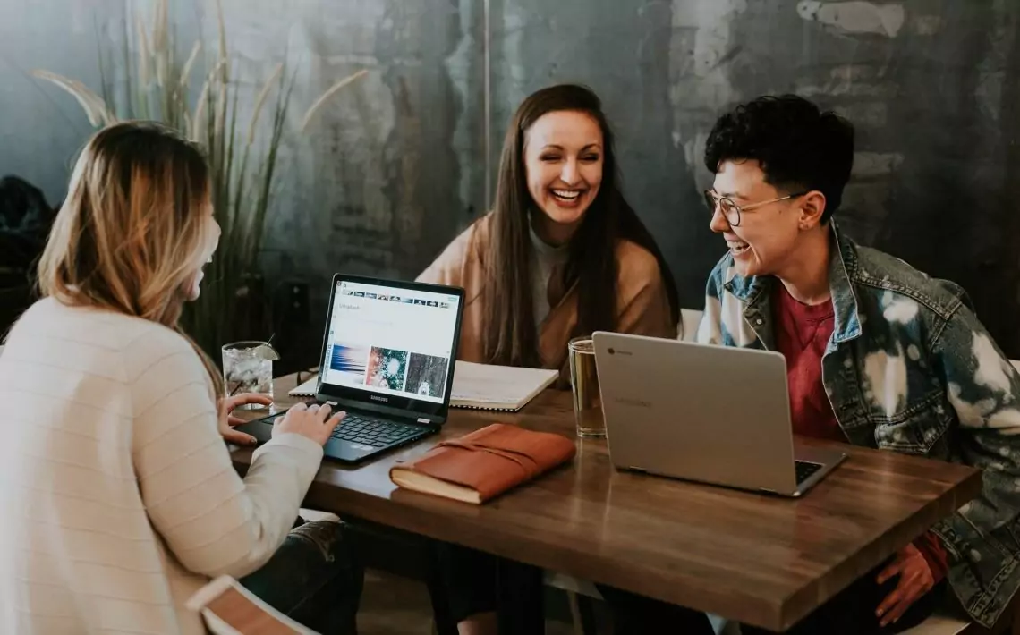 3 women sitting around a table with tablets learning English
