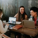 3 women sitting around a table with tablets learning English