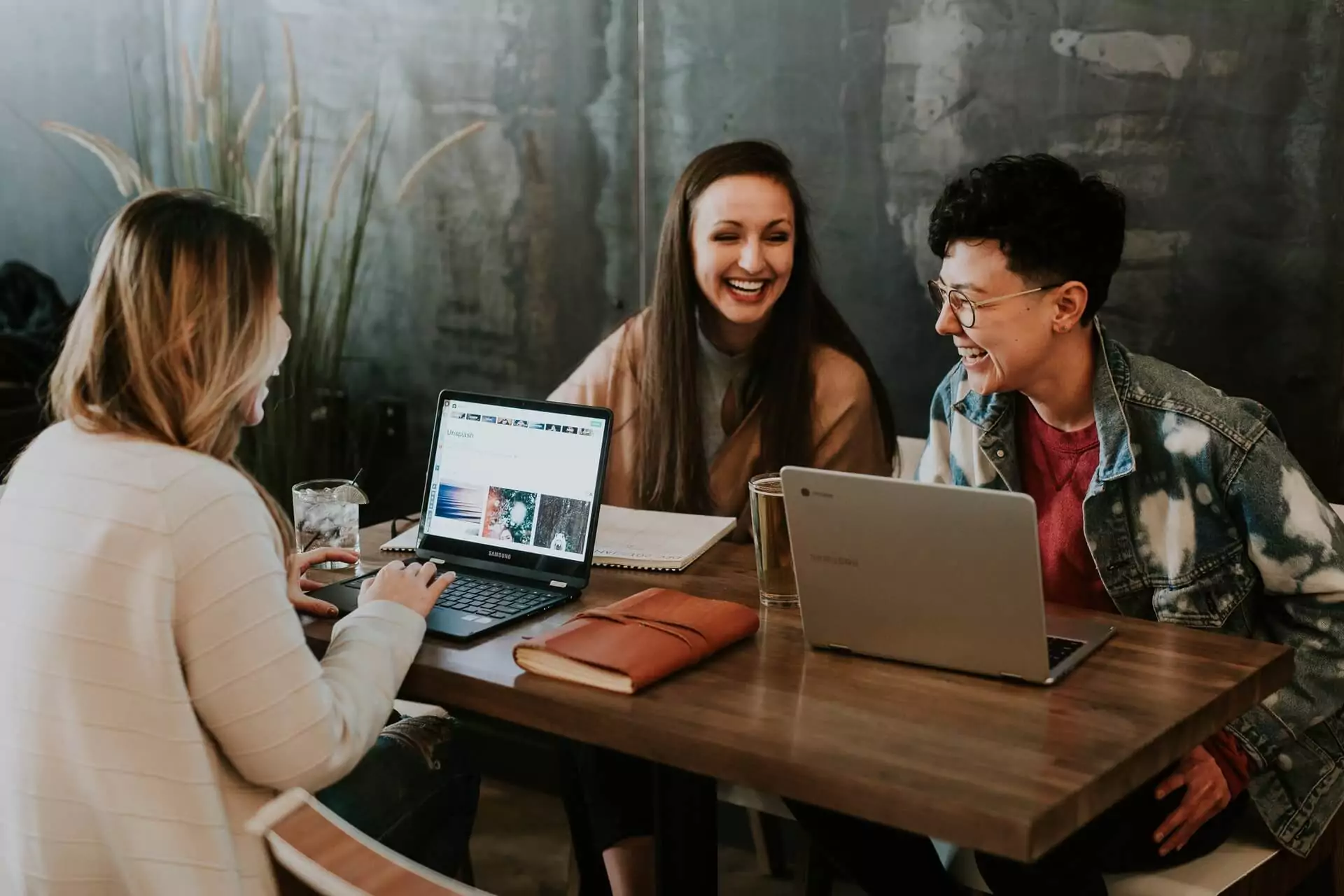 3 women sitting around a table with tablets learning English